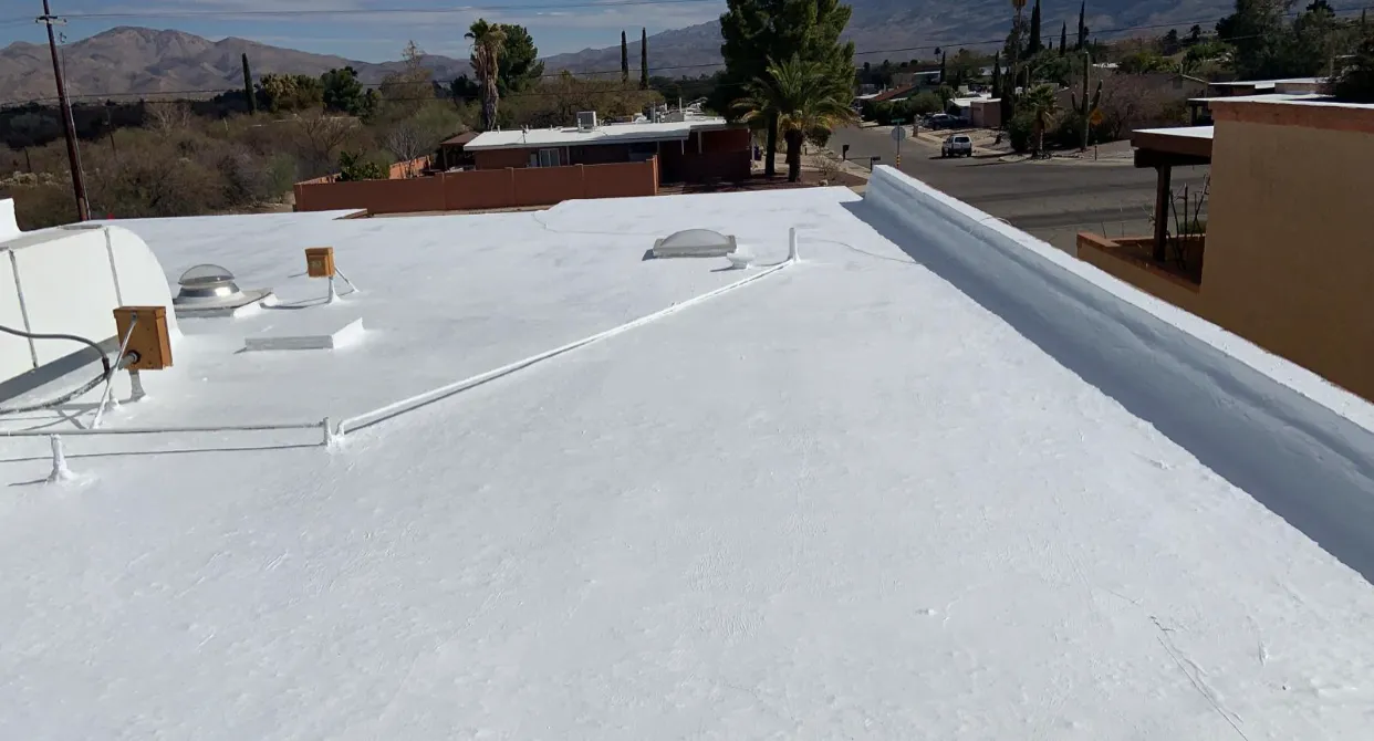 Completed white elastomeric roof coating on a flat roof in Tucson with the Santa Catalina Mountains visible