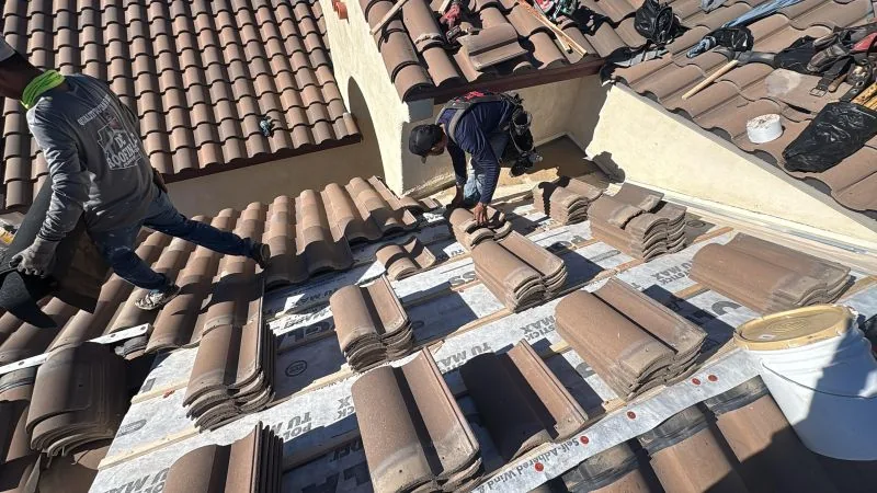 Two roofers installing clay tiles on a Tucson residential roof